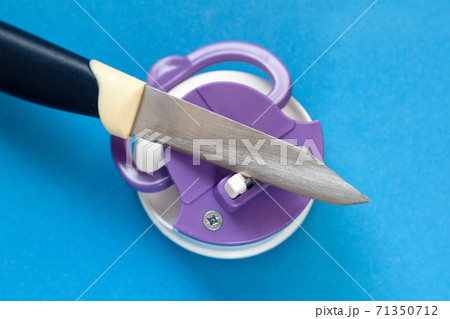 Kitchen knife and compact knife sharpener on blue background 71350712