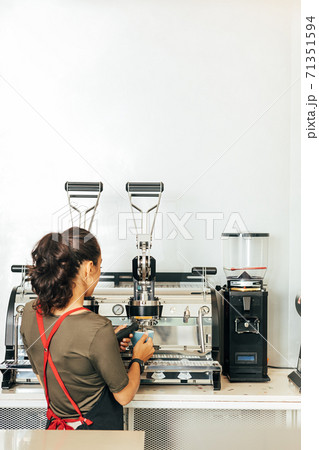 Back view of a female barista making coffee. Woman in apron working in a small coffee shop. Back view of a female barista making coffee. Woman in apron working in a small coffee shop. 71351594