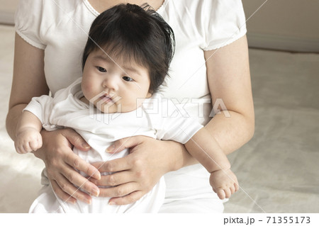 30代の母親と、膝の上に座る赤ちゃん、0歳、生後四か月、女の子 71355173
