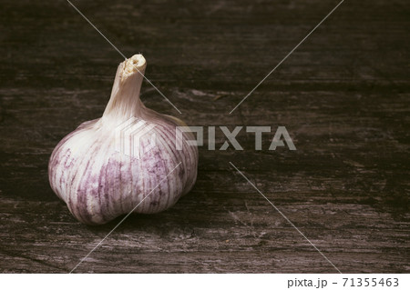 Bulb of garlic is standing on an old wooden table 71355463