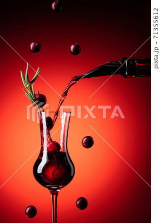 Cranberry liquor is poured from a bottle into a glass. 71355612