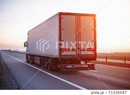 A truck with a trailer carries a groupage cargo on the highway against the backdrop of sunset. Concept of classification of transported goods, logistics, cargo handling 71356087