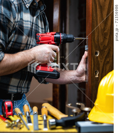 Carpenter at work repairs and installs the door lock. Carpentry. 71356986