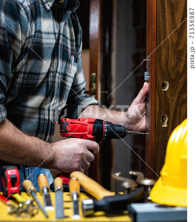 Carpenter at work repairs and installs the door lock. Carpentry. Carpenter at work repairs and installs the door lock. Carpentry. 71356987