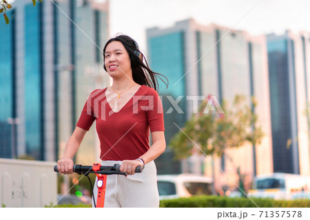 Woman having a ride on electric scooter for transportation Woman having a ride on electric scooter for transportation 71357578