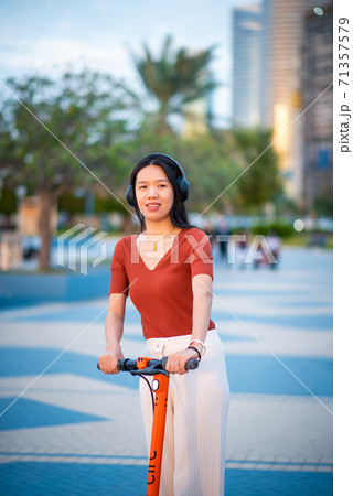 Woman using electric scooter for transportation in a modern city Woman using electric scooter for transportation in a modern city 71357579