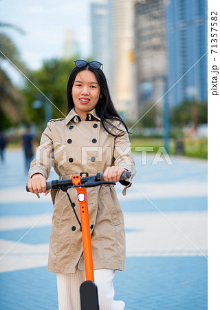 Woman using electric scooter for transportation in a modern city Woman using electric scooter for transportation in a modern city 71357582
