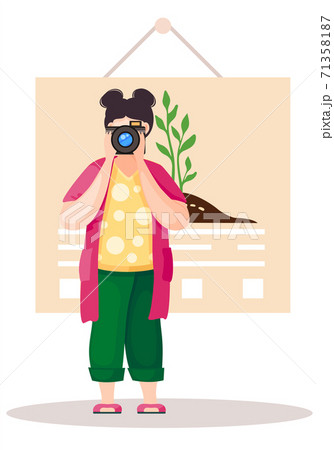 Girl standing and adjusting the lens. Photographer with poster with a planted tree on background Girl standing and adjusting the lens. Photographer with poster with a planted tree on background 71358187