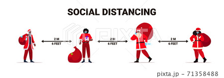 people in santa claus costumes keeping social distance to prevent coronavirus new year christmas holidays celebration 71358488