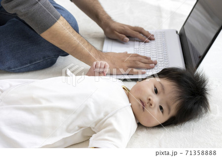 パソコンを使う父親と、横になる赤ちゃん、0歳、生後4か月、女の子 パソコンを使う父親と、横になる赤ちゃん、0歳、生後4か月、女の子 71358888