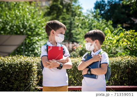 two boys, schoolchildren in black school uniforms with backpacks in a medical mask go to school independently, hold hands, friendship concept, study concept during coronavirus, back to school two boys, schoolchildren in black school uniforms with backpacks in a medical mask go to school independently, hold hands, friendship concept, study concept during coronavirus, back to school 71359051