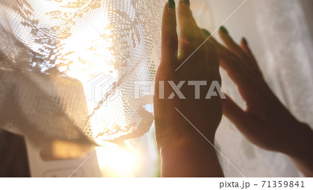 Hands pulling a window curtain for warm morning light. Young woman opening curtains. Close up. Female hands open window curtain in morning. Hands pulling a window curtain for warm morning light. Young woman opening curtains. Close up. Female hands open window curtain in morning. 71359841