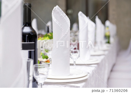white napkins on plates on a served Banquet table with dishes 71360206