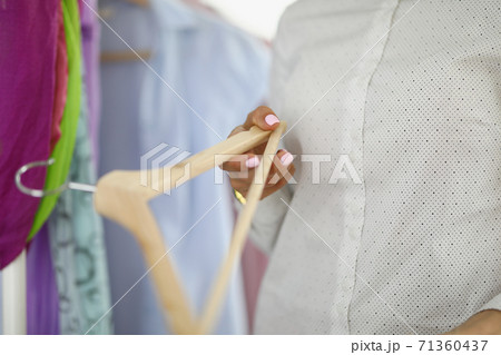 In female hand clothes hanger on background of clothes. In female hand clothes hanger on background of clothes. 71360437