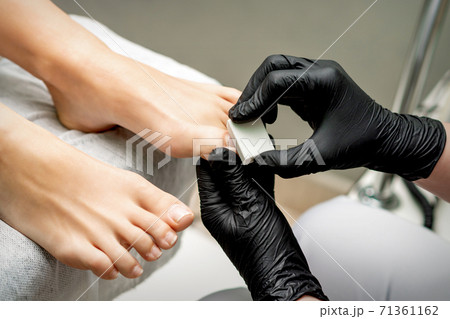 Pedicurist buffing toenail of woman Pedicurist buffing toenail of woman 71361162