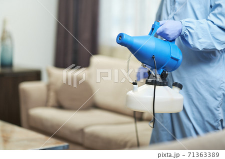 Worker wearing protective overalls while disinfecting a hotel apartment Worker wearing protective overalls while disinfecting a hotel apartment 71363389