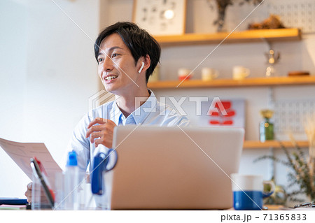 テレワーク　自宅のリビングでweb会議をする笑顔の若い男性 71365833