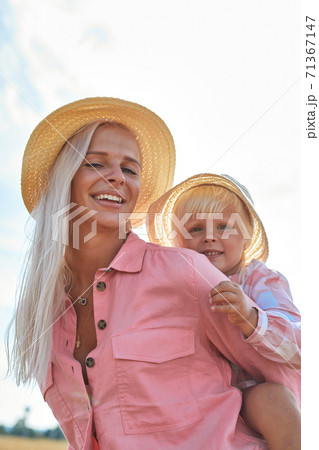 happy mother holding baby smiling on a wheat field in sunlight 71367147