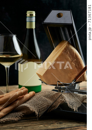 cheese as a perfect gourmet appetizer to a glass of white wine: bread sticks, parmesan served on a wooden board, on a black background 71367181