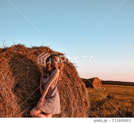 Portrait of young sexy woman with red hair on the haystack in morning sunlight, countryside. Beautiful woman in a dress sits on a haystack. Cottagecore Portrait of young sexy woman with red hair on the haystack in morning sunlight, countryside. Beautiful woman in a dress sits on a haystack. Cottagecore 71369903