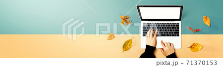 Autumn leaves with person using a laptop computer Autumn leaves with person using a laptop computer 71370153