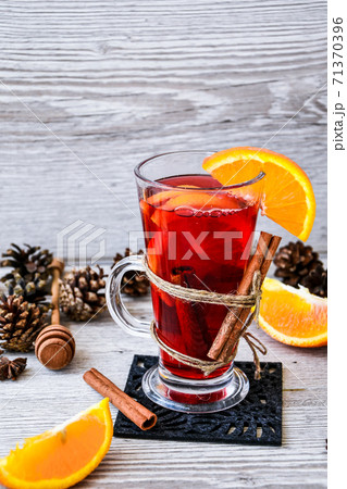 Christmas mulled wine with spices and orange on wooden rustic background. Selective focus. Anise stars and cinnamon sticks. Christmas cones. 71370396