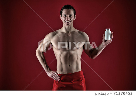 Man with strong belly hold pill jar. Red. Presenting product. Power and energy. Fitness 71370452