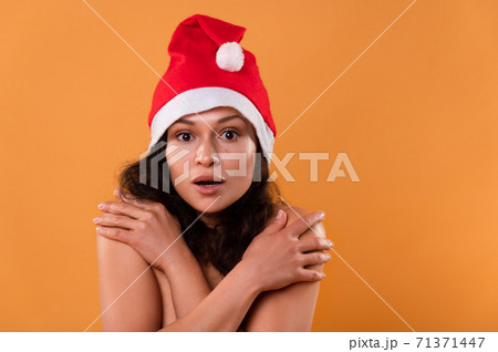 A young woman in a Santa Claus hat. Portrait on a yellow background. Christmas concept. A young woman in a Santa Claus hat. Portrait on a yellow background. Christmas concept. 71371447