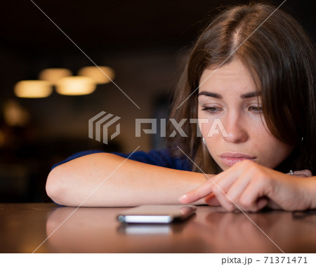 The sad woman has laid her head on the table and is waiting for a phone call The sad woman has laid her head on the table and is waiting for a phone call 71371471