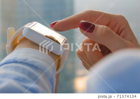 Woman hand using wearable white smart watch in office - close up side view Woman hand using wearable white smart watch in office - close up side view 71374134