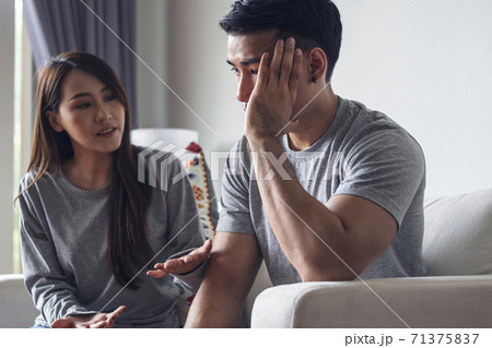 Unhappy young man have problems being quarrel with his wife sitting on sofa together at living room. Unhappy young man have problems being quarrel with his wife sitting on sofa together at living room. 71375837