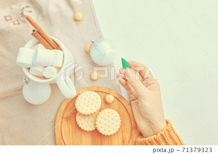 Women holds Christmas toy, cup of coffee, cookies and tablecloth on table. 71379323