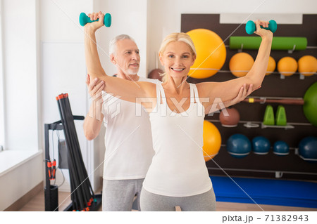Mature man instructing blonde woman in gym 71382943