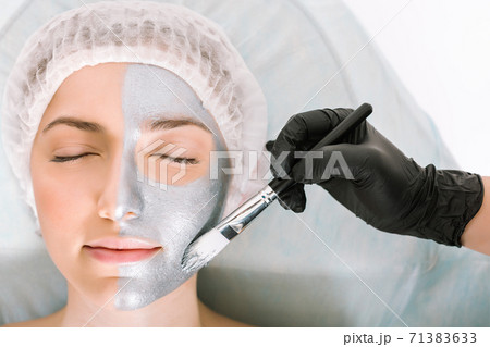 Beauty portrait of a girl lying on a medical table with her eyes closed, while applying a cosmetology mask to her face. The concept of rejuvenation and skin refreshment. 71383633