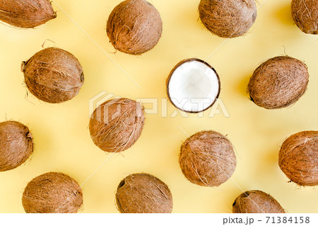 Pattern with coconuts and tropical palm leaves on yellow background. Tropical abstract background. Flat lay, top view. Pattern with coconuts and tropical palm leaves on yellow background. Tropical abstract background. Flat lay, top view. 71384158