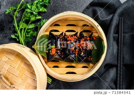 Black Dim sum dumplings in bamboo steamer. Asian cuisine. Black background. Top view Black Dim sum dumplings in bamboo steamer. Asian cuisine. Black background. Top view 71384341