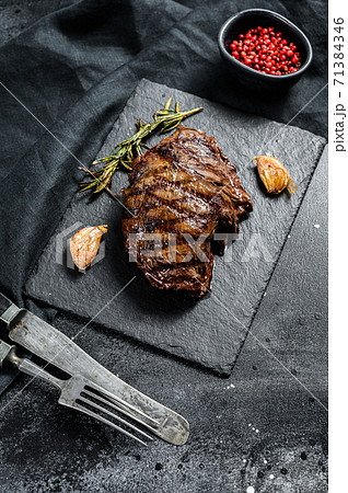 Grilled Flat Iron steak on a stone Board, marbled beef. Black background. Top view Grilled Flat Iron steak on a stone Board, marbled beef. Black background. Top view 71384346