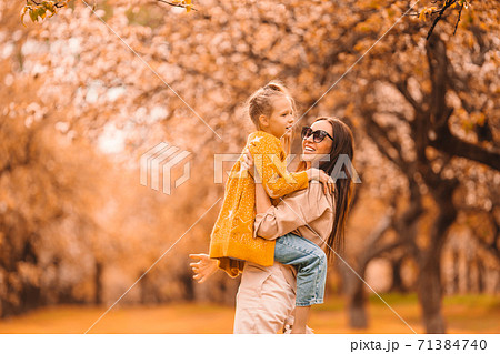 Little girl with mom outdoors in park at autumn day 71384740
