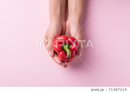 Red bell pepper holding by hand on pink background 71387214
