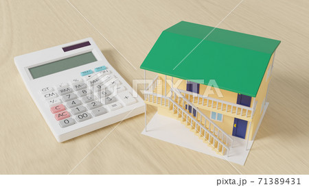 平面上に置かれたおもちゃのアパートと電卓 71389431