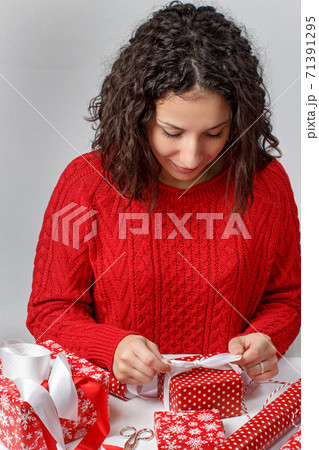 Woman ties a ribbon bow on a wrapped present Woman ties a ribbon bow on a wrapped present 71391295