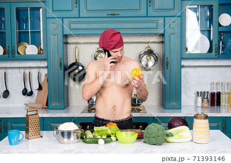 Macho cook with sexy torso talk on mobile phone in kitchen. Chef  71393146