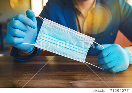 Businessman hands in protective gloves hold a medical mask, close-up Businessman hands in protective gloves hold a medical mask, close-up 71394077