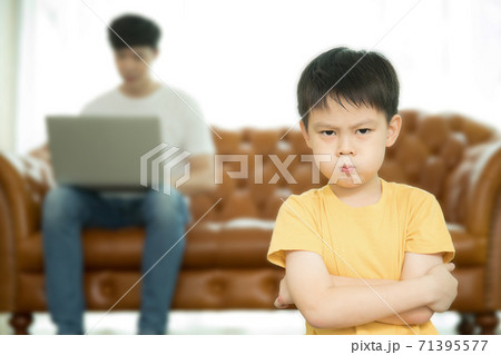 パソコンで仕事ばっかりしている父親に不満の表情をする小さい男の子 71395577