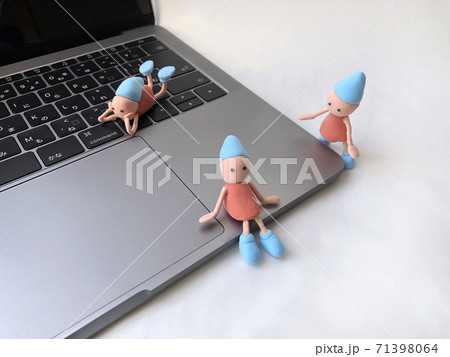 シルバーパソコンと手作り粘土のかわいい小人たちの写真素材
