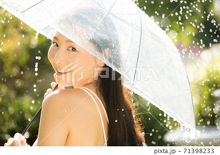 傘を持って雨の中を楽しむ綺麗な女性の写真素材