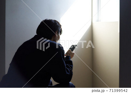 座ってスマホを見る男性の後姿 71399542