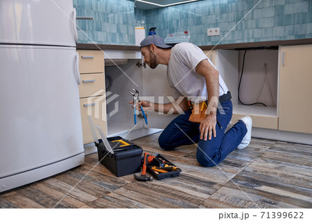 Young caucasian man working with wrench in kitchen drawer 71399622