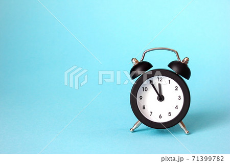 The clock is 23-55. Black alarm clock on a blue background. The concept of the New year and Christmas. 71399782