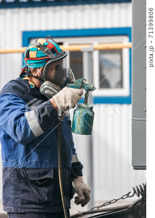 Industrial work. Priming of metal products from the compressor gun. A worker in overalls and a 71399806